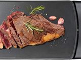 une photo d'un steak sur un barbecue, agrémenté d'herbes et d'épices