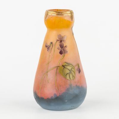 un petit vase sur lequel sont peintes des fleurs sur un fond blanc