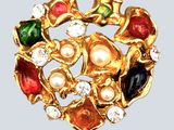 une image représentant une broche en or ornée de pierres multicolores et de perles