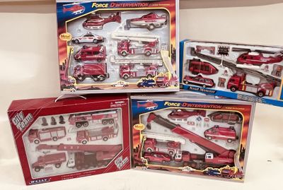 Trois camions de pompiers miniatures dans leur boîte et un camion de pompiers sont posés sur une table