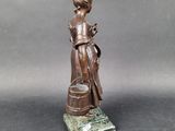 bronze statue of a woman holding a bucket and a bucket