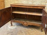 a wooden cabinet with a door open on a brick floor