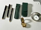 une montre, un stylo, un étui à montre, une montre et d'autres objets posés sur une table