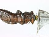 someone is holding a knife with a carved handle on a white surface
