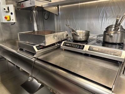 un plan de travail en acier inoxydable sur lequel sont posés des casseroles et des poêles, dans une cuisine professionnelle