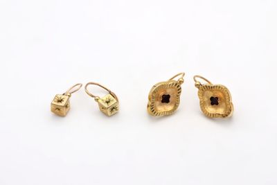 a pair of gold earrings and a pair of earrings on a white surface