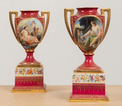 deux vases rouges décorés de peintures, posés sur une table