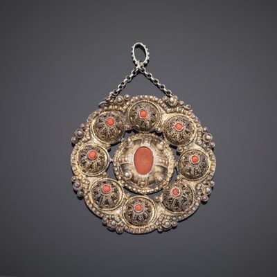 a close up of a necklace with a red stone in the center