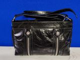 black leather purse with zippers on top of it on a table