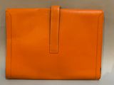 an orange leather clutch bag with a long strap