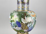 a vase that has a bird and flowers on it