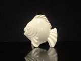 une figurine blanche représentant un poisson sur un fond noir