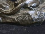 a bronze statue of a woman laying on a rock