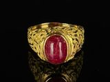 a close up of a gold ring with a red stone