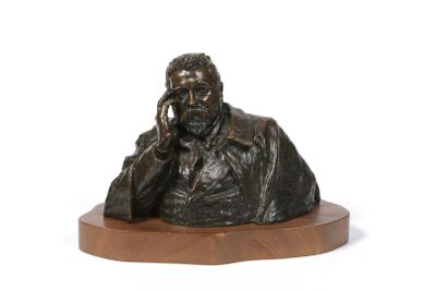 a bronze statue of a man sitting on a wooden base