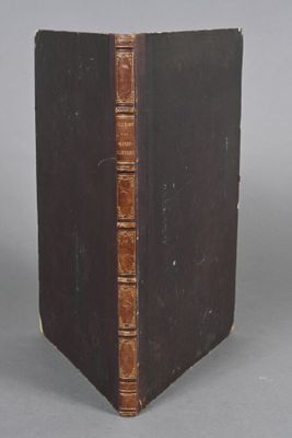 an old book sitting on top of a table next to a gray wall