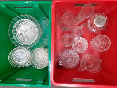two plastic containers filled with empty glassware on a table