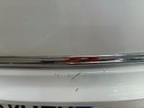 the rear end of a white car with a red stripe on it