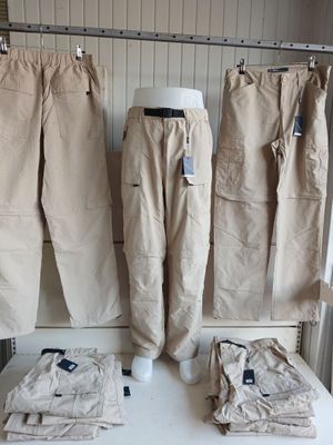 three pairs of khaki pants hanging on a rack in a clothing store