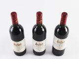 three bottles of wine sitting next to each other on a white surface