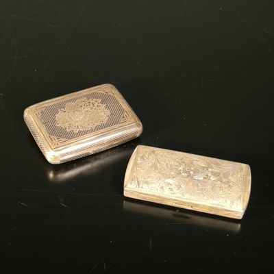 deux étuis à cigarettes en argent posés sur une table noire