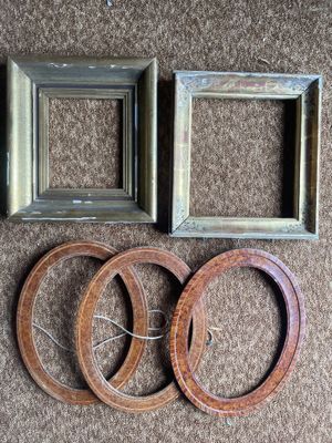 three frames and a pair of wooden rings on a brown carpet