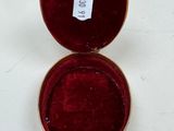 a small red box with a gold lid on a white table