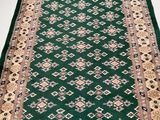 a green rug with a gold border on a white floor