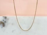 un collier à chaîne en or posé sur une dalle de marbre