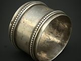 un rond de serviette ancien en argent, orné de bords perlés sur fond noir