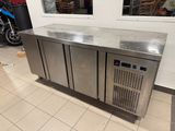 a stainless steel counter with three doors and a motorbike in the background