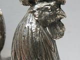 une statue en argent représentant un coq coiffé d'un chapeau