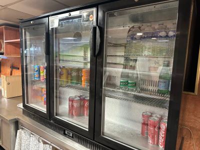 Des bouteilles de soda et de boissons gazeuses sont rangées dans le réfrigérateur d'un restaurant.