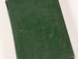 an old green book sitting on top of a white table