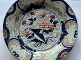 a blue and orange plate with a bird and flowers on it