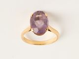 une bague en or jaune sertie d'une pierre violette