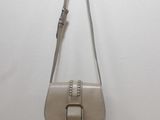 a white purse hanging on a wall with a metal hook
