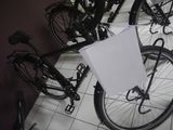 a bicycle that has a sign attached to it ' s front wheel