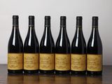 six bouteilles de vin sont posées sur une table devant un mur blanc