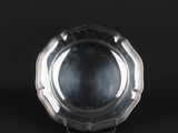 a silver plate on a stand against a black background