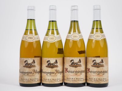 quatre bouteilles de vin sont alignées sur une surface blanche