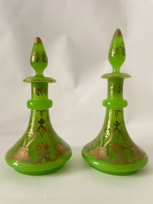 une paire de bougeoirs en verre vert ornés de motifs dorés