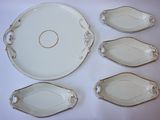 plusieurs pièces de porcelaine blanche ornées de bordures dorées, disposées sur une table blanche
