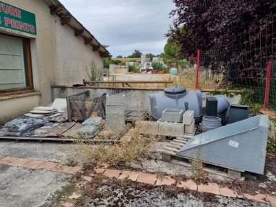 un tas d'ordures devant un immeuble, à côté d'un autre immeuble