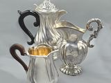 two silver coffee pots and a silver pitcher on a grey background