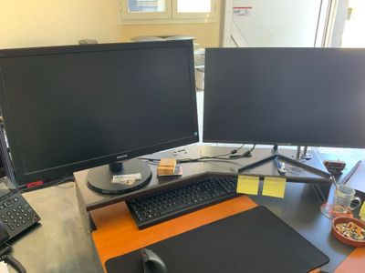 un bureau équipé de deux écrans, d'un clavier, d'une souris et d'un tapis de souris