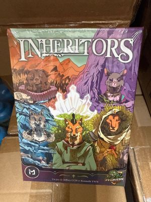 La boîte du jeu de société « Les Héritiers » est posée sur une boîte en carton