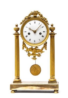 a gold clock with a white face on a stand