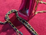 a pink purse with a chain around it on a red surface