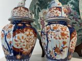 trois vases posés sur une étagère, à côté d'une assiette et d'une horloge